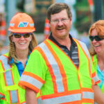 Three communication strategists with hard hats on in Aspen as they smile in conversation strategy, communication, during captivating photo moment.